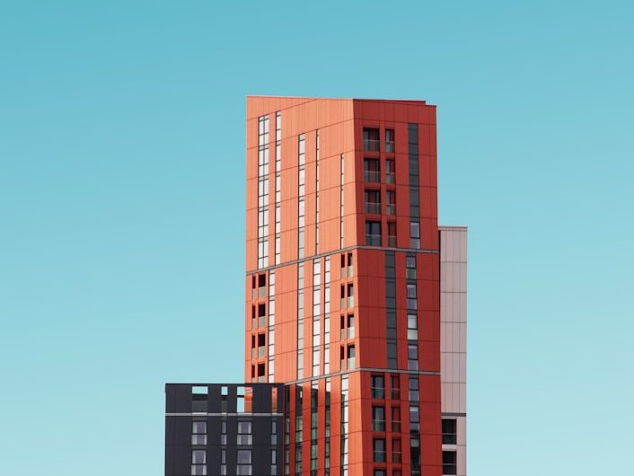 Hochhaus in verschiedenen Farbtönen vor blauem Himmel.